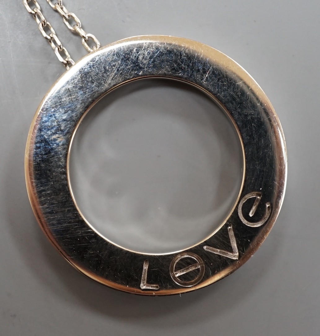 A modern Italian Cartier 750 white metal 'Love' circular pendant, 24mm, numbered CRD612779, on a 750 white metal fine link chain, 46cm, 10.8 grams.